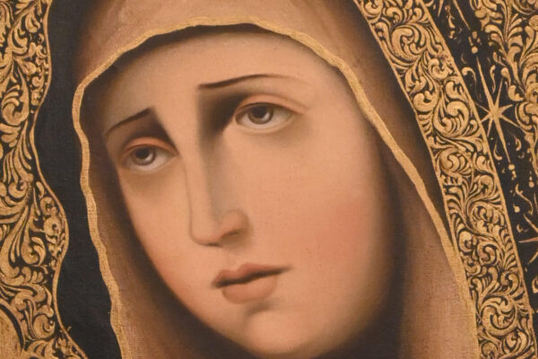 Pintura religiosa de la Virgen María con manto oscuro, halo dorado decorado y marco de madera tallada en tonos oscuros.